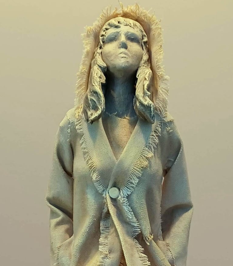 Clay and canvas sculpture of a female figure gazing upwards, wearing windswept, ragged clothes.