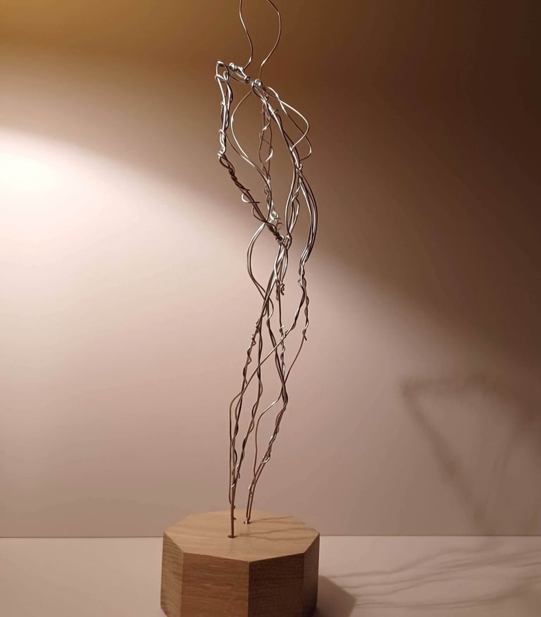 A wire sculpture of a complete female figure, standing with hands on hips