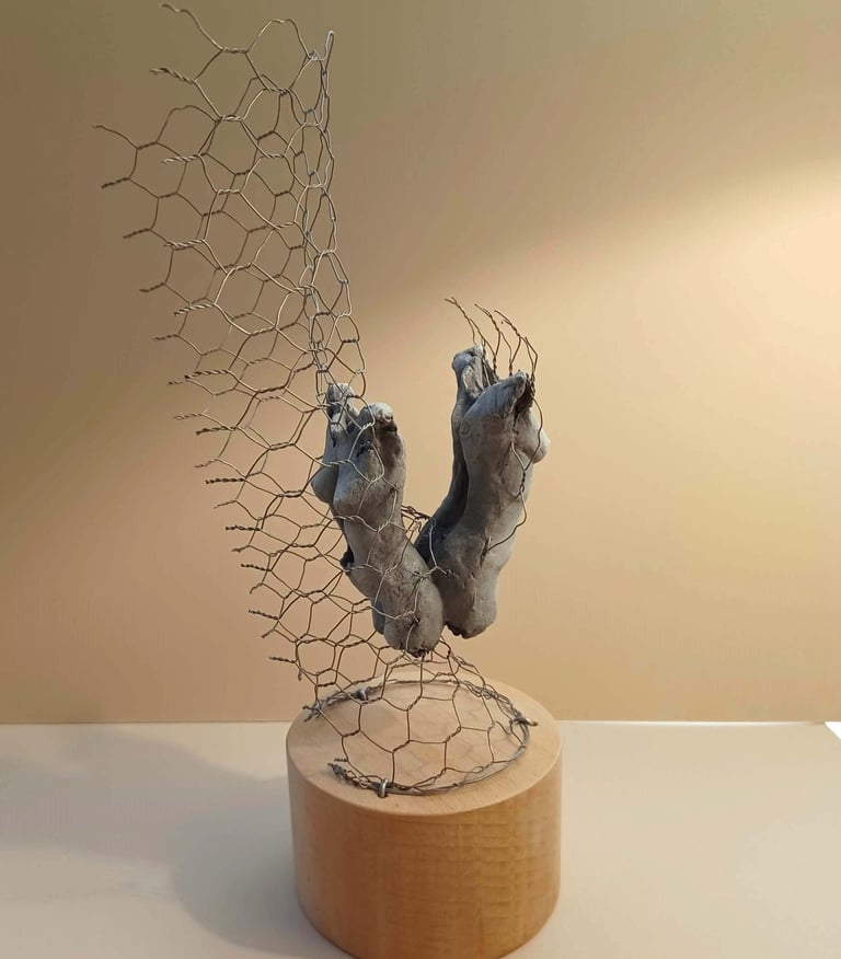 A sculpture of two female torsos, back to back, surrounded by wire netting, painted blue-greys