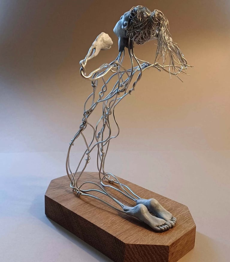 A wire sculpture of a complete kneeling female figure with clay hands, face and feet, arms raised