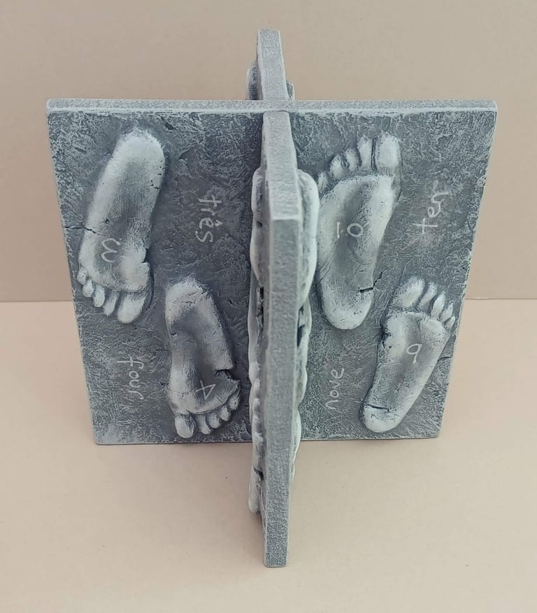 Two intersecting relief sculptures forming an X shape, and depicting three dimensional footprints.