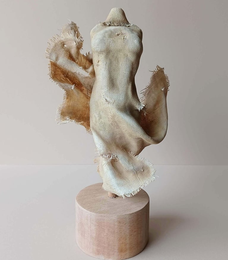 Clay and canvas sculpture of a female torso, wearing windswept, ragged clothes.