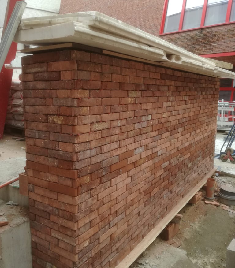 Mur en briques rouges en cours de montage, maçonnerie traditionnelle soignée sur chantier de rénovat