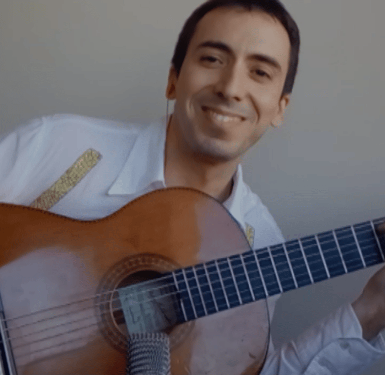 Paco sonríe mientras muestra su guitarra.