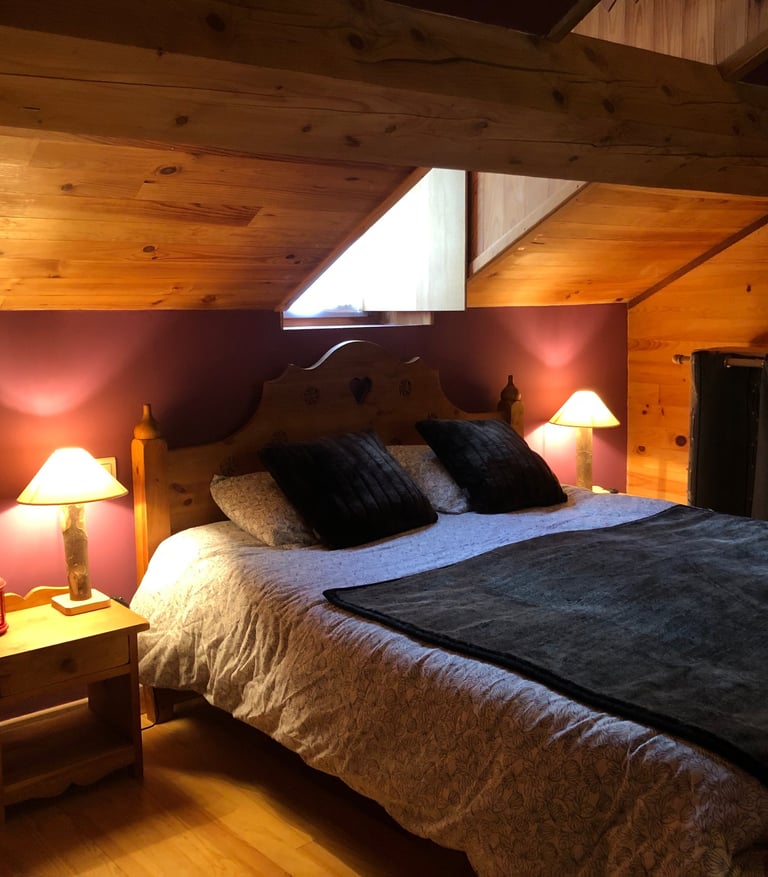 a bedroom in the Russell barn with a mountain-style bed two bedside tables and two wooden lamps