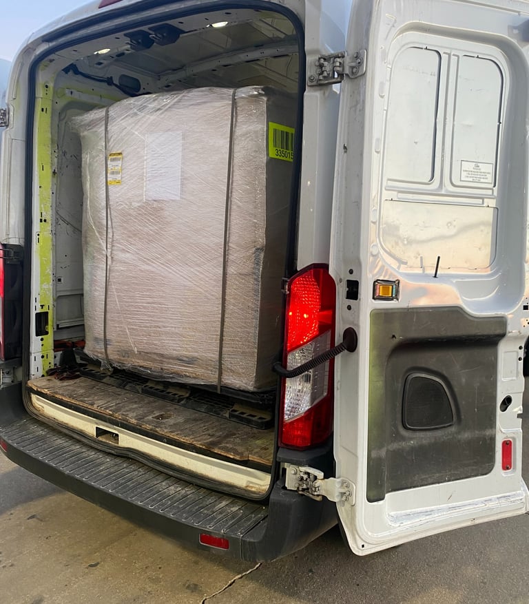 Rear view of a white delivery van with its rear doors open showing a large shrink-wrapped pallet