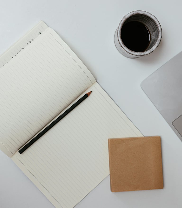 Werkplek van schoolleider met laptop, koffie en notitieboekje voor korte morele reflectie