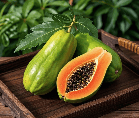 Fresh ripe papaya fruit halved with black seeds and green leaves on a rustic wooden tray.