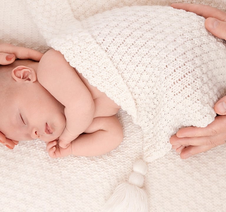 photo de bébé doucement enveloppé des mains de ses parents