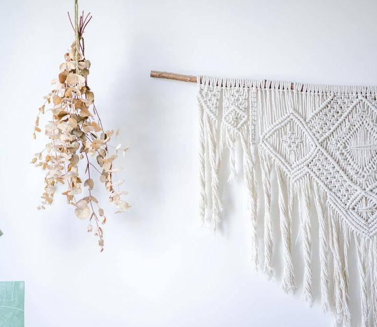 adorno artesanal hecho con macramé sobre una pared blanca y madera