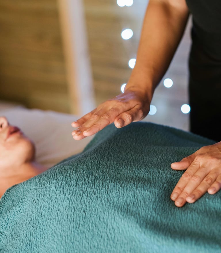 Une femme reçoit une séance de magnétisme, allongée sur une table de massage, détendue et concentrée.
