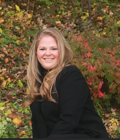 team member from Rise Up Window Coverings smiling outdoors during fall season