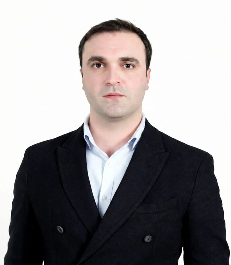 Professional headshot of a man in a black blazer and light blue shirt against a white background.