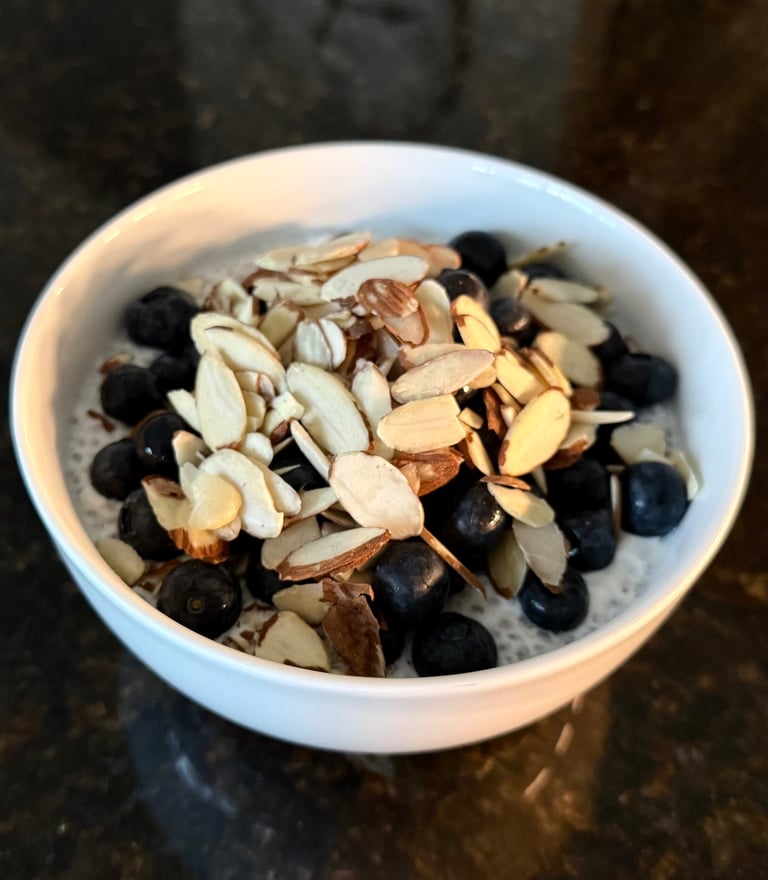 Greek yogurt with soaked chia seeds, blueberries, and sliced almonds in a white bowl.