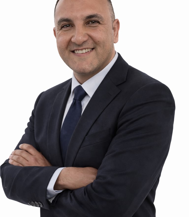 A smiling professional businessman in a navy blue suit and tie with arms crossed.