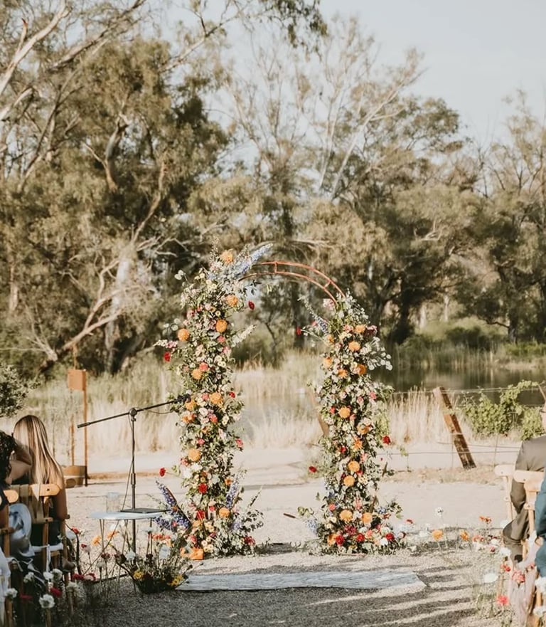 Arco floral decorando ceremonia en jardín natural.
