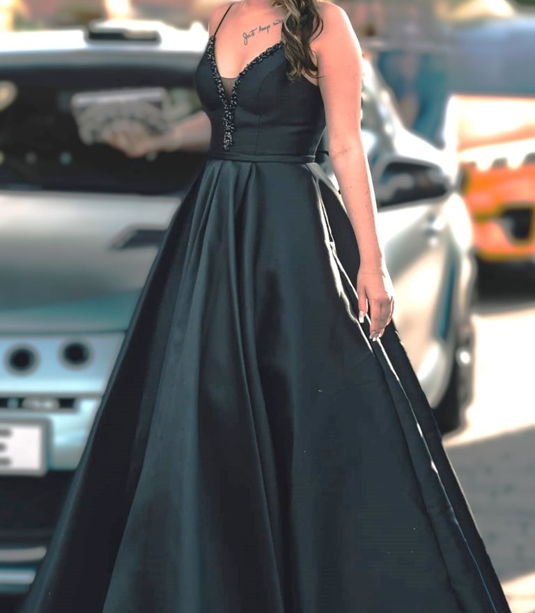 a woman in a black dress standing in front of a car