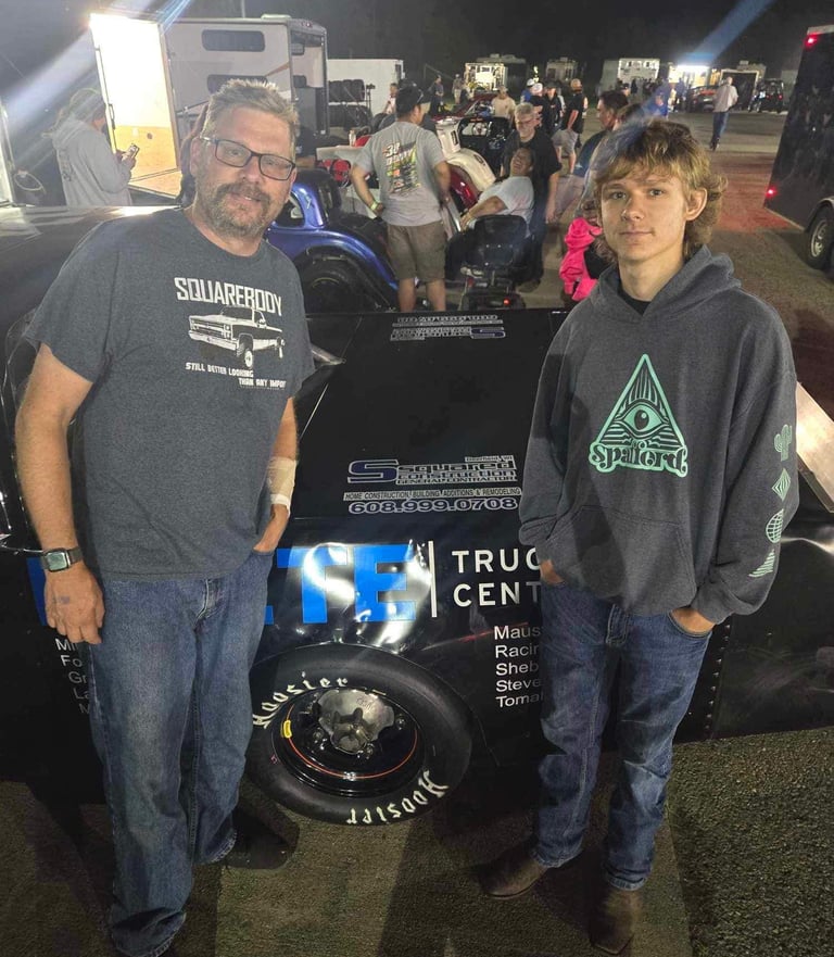 Owner and his father standing in front of a race car sponsored by S Squared Construction, featuring 