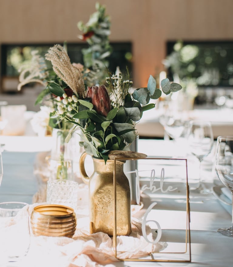 Dekortierter Tisch mit goldener Vase und Protea