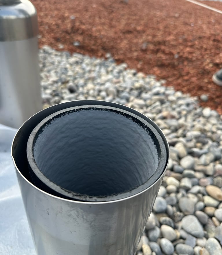 Eines fachgerecht mit Inliner sanierten Edelstahlrohrs mit glatter schwarzer Innenbeschichtung