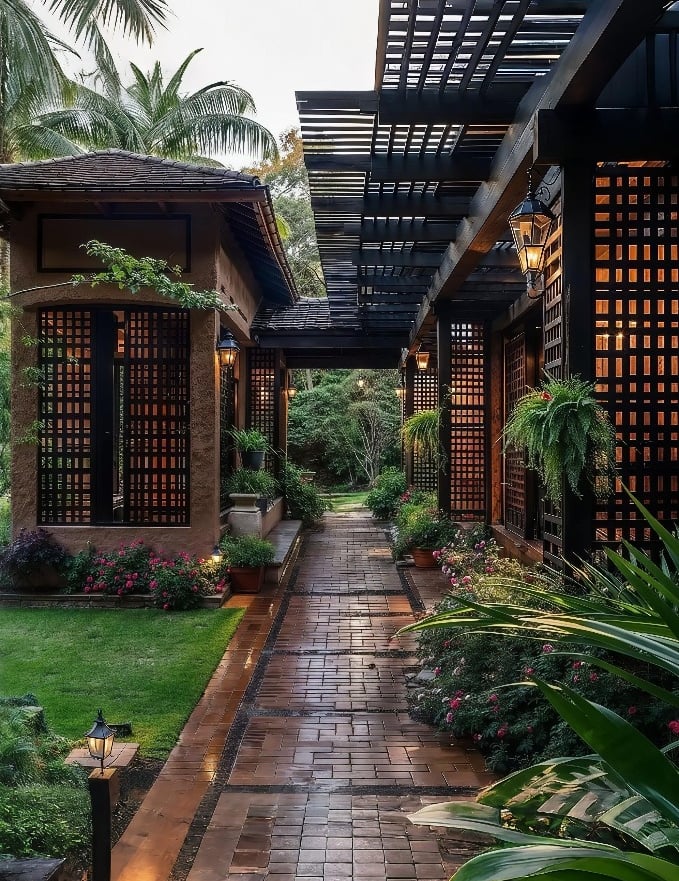 Luxury tropical villa walkway with a black pergola, stone pavers, and lush garden landscaping.