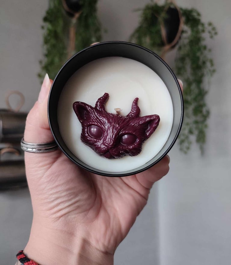 Bougies à la cire blanche, avec un fondant en forme de chat cornu, bordeaux. Contenant en métal noir