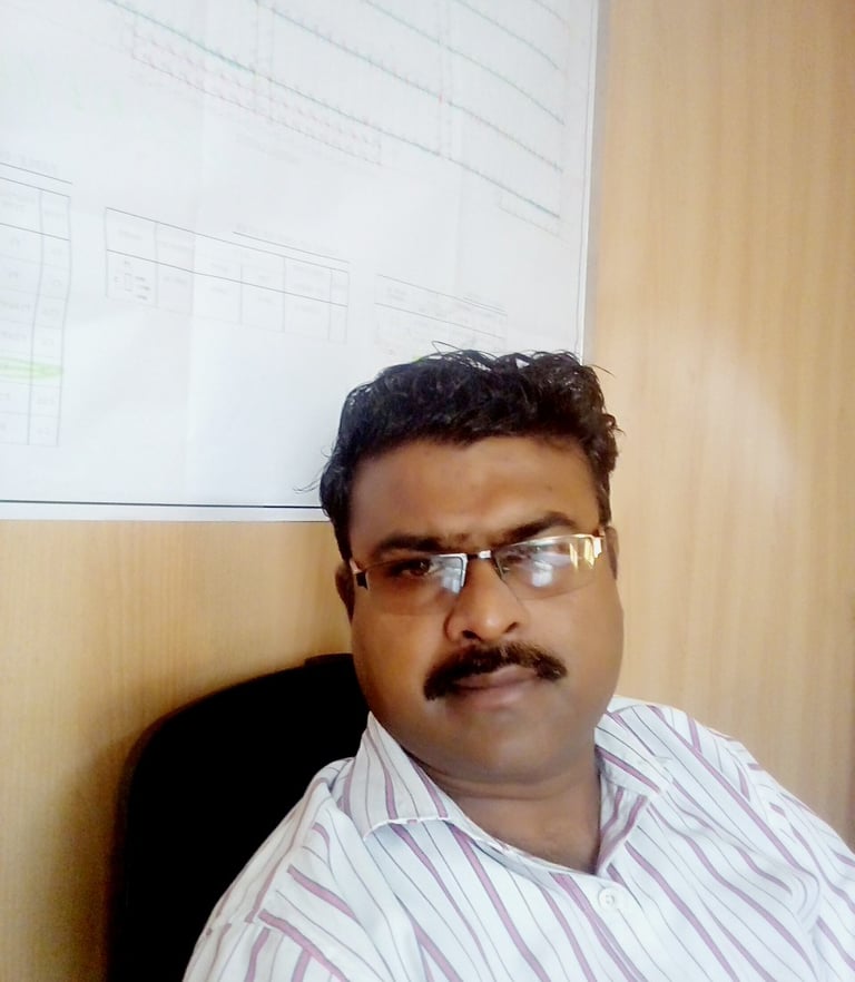 a man with glasses and a mustache sitting in front of a white board
