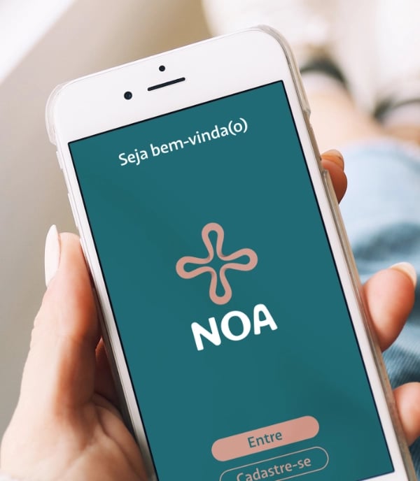 Uma mão segurando um celular mostrando a tela inicial de um aplicativo.
