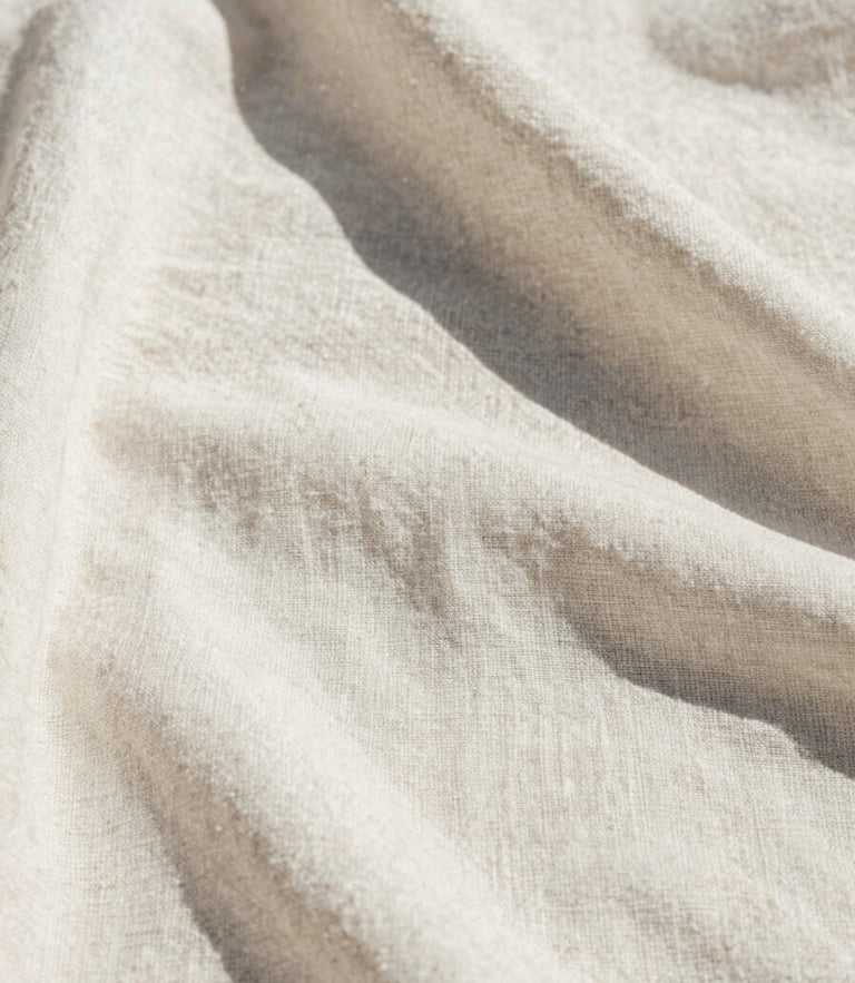 Extreme close-up of raw linen fabric texture, sun-bleached white, harsh Mediterranean midday sun casting sharp shadows, warm minimalist editorial fashion photography