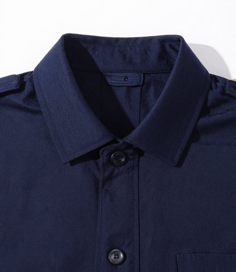 Crisp, high-key studio photograph of a sharp, well-fitting dark navy uniform collar with detailed embroidery stitching, bright natural daylight, 35mm.
