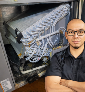Professional HVAC technician standing next to a frozen air conditioner evaporator coil.