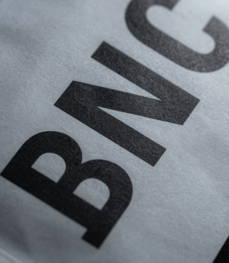 Extreme close-up of crisp typography on a physical packaging prototype, flat studio lighting, sharp high-contrast shadows, cool graphite tones.