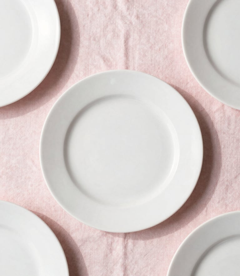 Overhead flat-lay of a minimalist table setting with soft blush pink linens, delicate white plates, and natural daylight casting gentle shadows, 35mm
