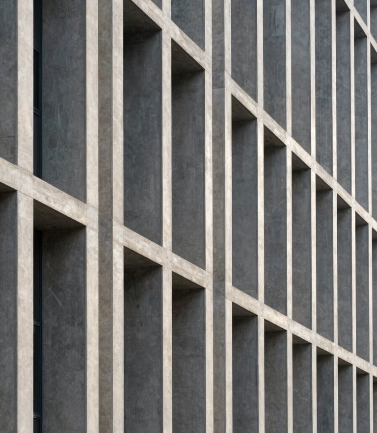 A high-contrast, wide architectural shot of a modern concrete and steel building facade. Sharp diagonal shadows cut across clean vertical lines. Cool morning natural light emphasizes the structural grid.