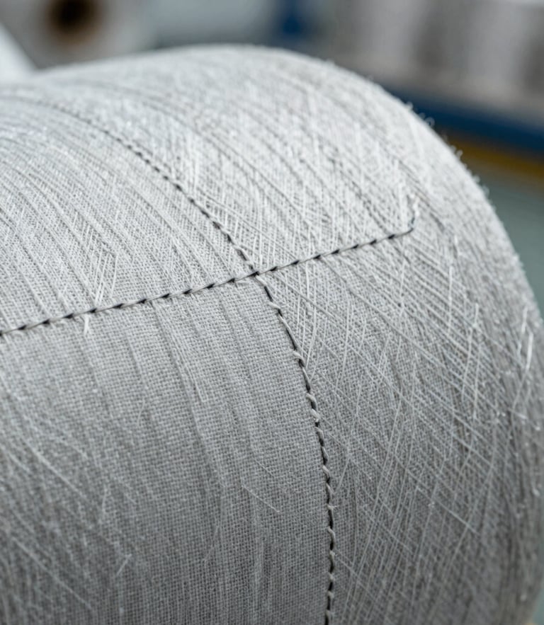 Detailed macro shot of heavy-duty seams on raw linen, illuminated by cool natural daylight in a clean industrial setting.
