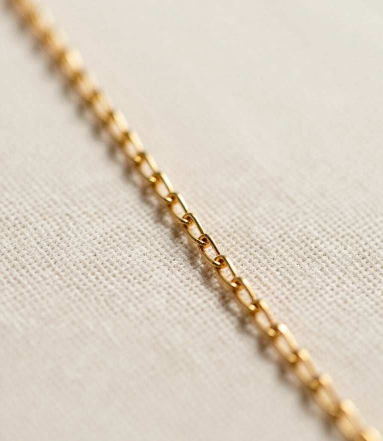 Extreme macro close-up of an ultra-fine gold-plated chain resting on a textured linen surface, soft diffused daylight, shallow depth of field