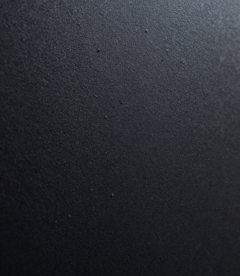 Extreme close-up of a freshly cured matte black textured powder-coated steel surface, showing fine physical grains under dramatic directional lighting.