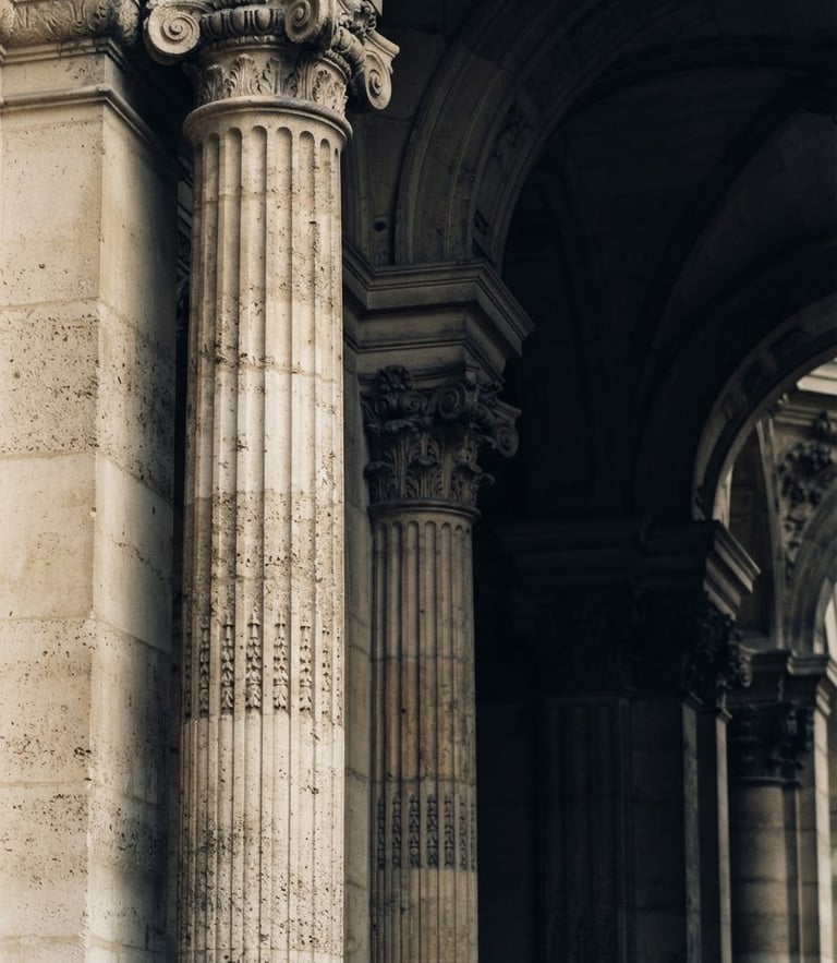 Macro detail of classic stone architectural columns and deep shadows, soft overcast daylight, muted navy and warm champagne tones, 35mm.