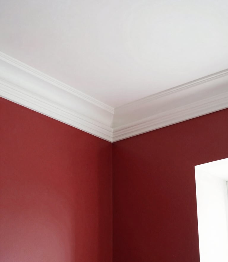 Clean architectural photography of a finished room interior, crisp white crown molding against deep red walls, bright natural daylight, sharp focus, 35mm