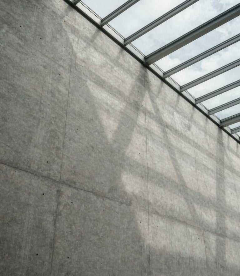 Wide-angle architectural crop of a concrete wall meeting a glass ceiling, dramatic light-and-shadow play, overcast daylight.
