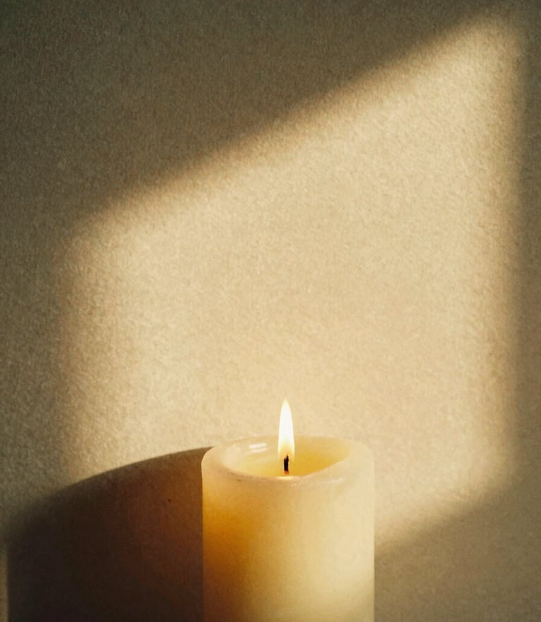 Close-up of a lit candle casting soft shadows on a textured plaster wall, warm golden-hour light, intimate 35mm film grain