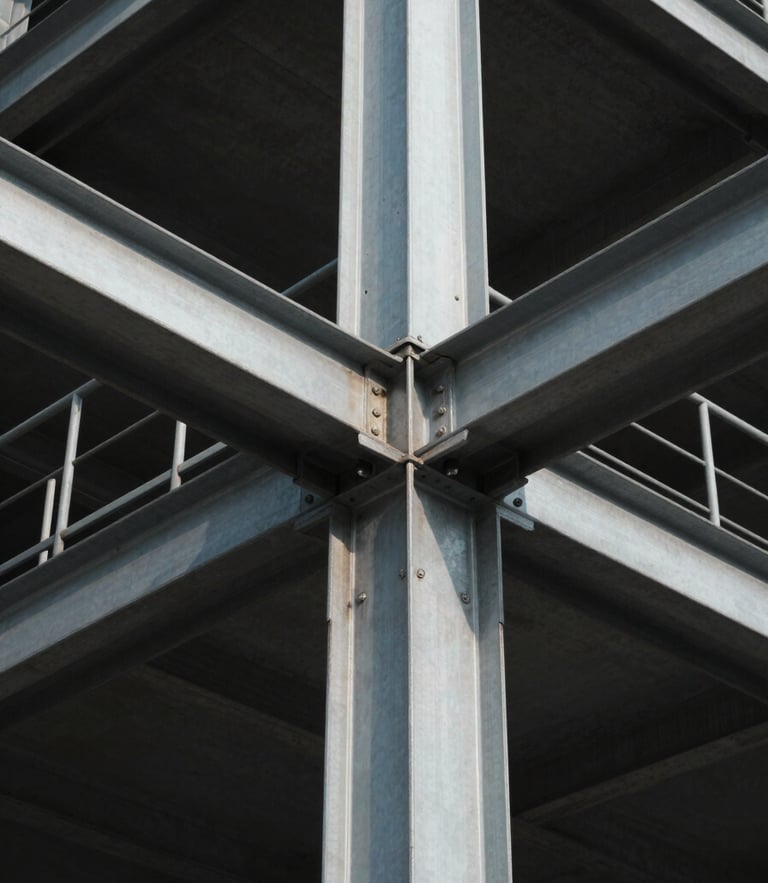 A high-contrast, low-angle architectural shot of sharp steel and concrete structural joints under cool, crisp daylight with deep shadows.
