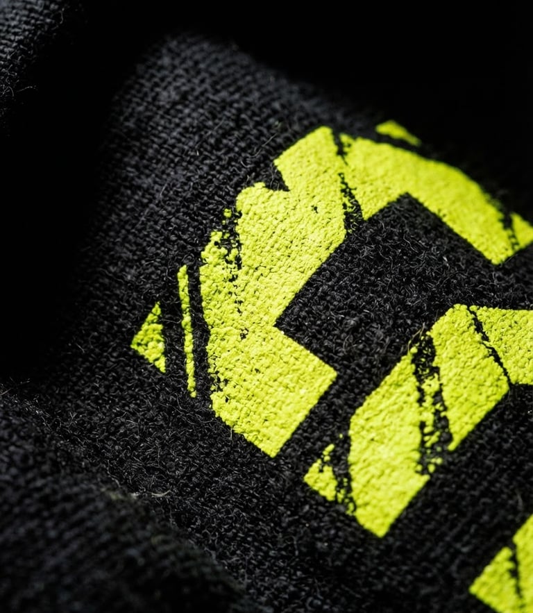 High-contrast urban product photography, macro shot of thick black cotton fabric with crisp screen printing in neon yellow, dramatic studio lighting, deep shadows, 35mm