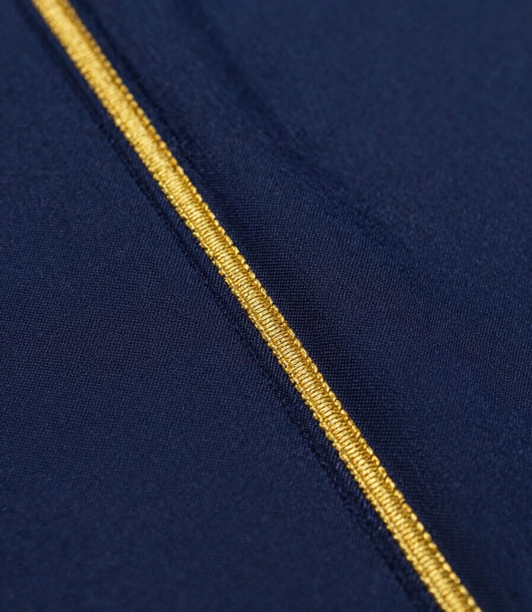 Macro shot of premium deep navy fabric with precise gold stitching, high-contrast studio lighting, crisp texture focus
