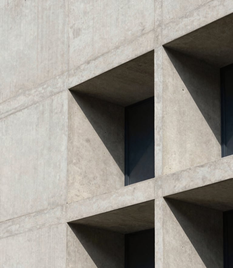 Architectural detail of a modern concrete facade with sharp shadows, soft natural daylight, minimalist structural lines, 35mm.
