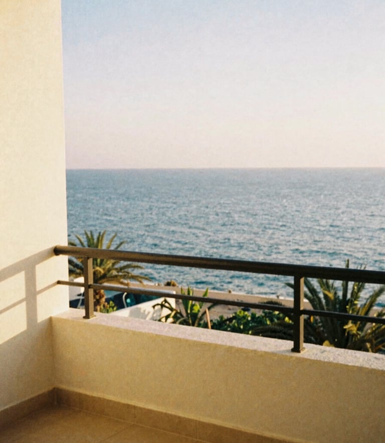 A quiet sun-drenched resort balcony overlooking the Mediterranean sea, warm golden hour light, soft coastal tones, 35mm film
