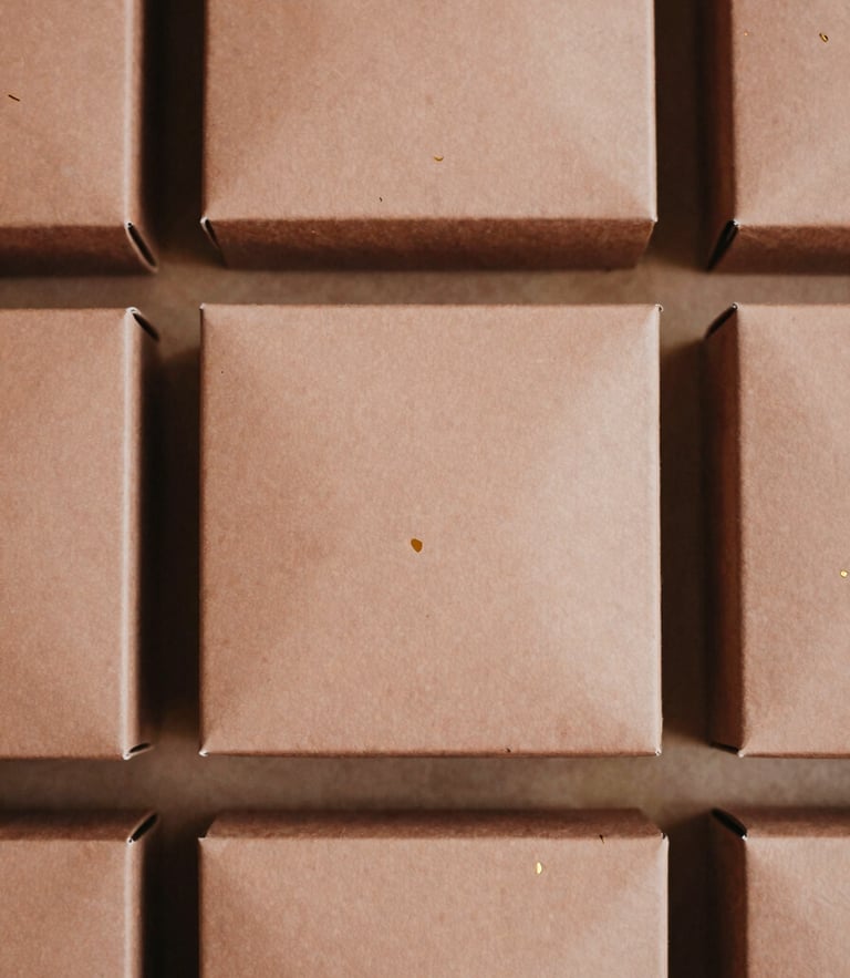 Overhead flat-lay of structured saffron gift boxes with clean gold foil-stamping, soft diffused natural side-light, warm desaturated clay tones, 35mm film.