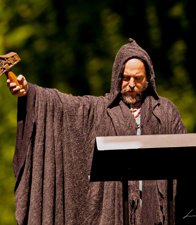 Oficiante vestido con túnica medieval marrón y capucha alzando una espada cerimonial durante una bod
