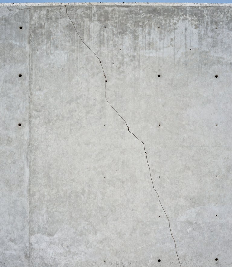 Straight-on level architectural photograph of a clean concrete basement wall with a hairline crack being prepared for injection, bright natural daylight, cool slate tones, crisp focus, 35mm.