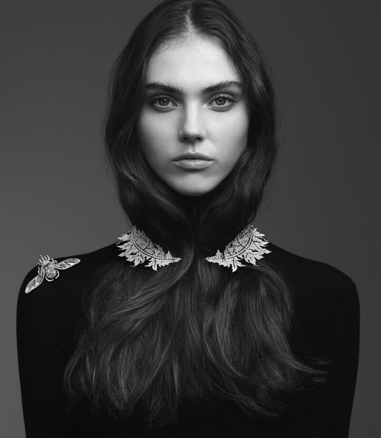 Model wearing leaf-shaped diamond jewelry on neckline and shoulder..